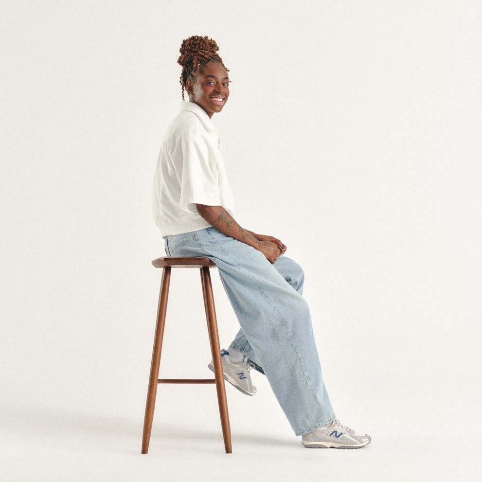 Can Burns sitting on a stool in a white studio enviornment.